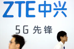 In this Sept. 26, 2018, file photo, visitors walk beneath the logo of Chinese technology firm ZTE at the PT Expo in Beijing.