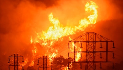 In this Dec. 16, 2017, file photo, flames burn near power lines in Sycamore Canyon in Montecito, Calif.