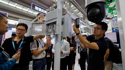 In this Oct. 29, 2019, photo, visitors look at the 5G mobile station and a surveillance camera by China's telecoms equipment giant Huawei at the China Public Security Expo in Shenzhen.