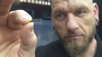 Jowan Osterlund of Biohax Sweden holds a microchip implant similar to those being offered to employees at Wisconsin software developer Three Square Market.
