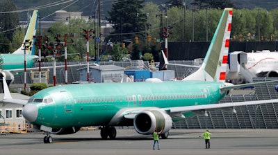 In this May 8, 2019, file photo workers stand near a Boeing 737 MAX 8 jetliner being built for American Airlines prior to a test flight in Renton, Wash. American Airlines CEO Doug Parker says his airline is feeling more confident that its grounded Boeing 737 Max jets will soon be approved to fly again.