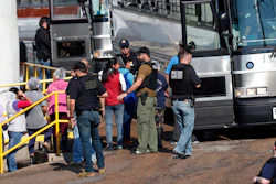 In this Wednesday, Aug. 7, 2019, file photo, handcuffed workers are escorted into a bus for transportation to a processing center following a raid by U.S. immigration officials at a Koch Foods Inc., plant in Morton, Miss. Three months after immigration agents arrested 680 Latino workers in a massive workplace sting at seven Mississippi chicken processing plants, a congressional committee plans a hearing into the raids and their effects, Thursday, Nov. 7, in Jackson, Miss.