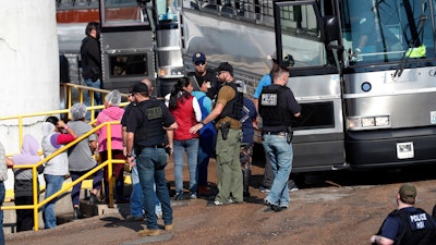 In this Wednesday, Aug. 7, 2019, file photo, handcuffed workers are escorted into a bus for transportation to a processing center following a raid by U.S. immigration officials at a Koch Foods Inc., plant in Morton, Miss. Three months after immigration agents arrested 680 Latino workers in a massive workplace sting at seven Mississippi chicken processing plants, a congressional committee plans a hearing into the raids and their effects, Thursday, Nov. 7, in Jackson, Miss.