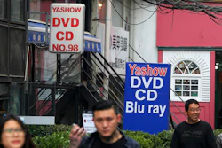 In this April 27, 2016, file photo, people walk past a shop selling pirated movie DVDs and music CDs in Beijing. China’s leaders have issued new, tougher guidelines for protection of patents, copyrights and other intellectual property.