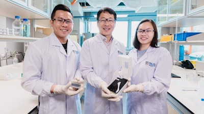 The NUS research team behind the novel algae detection device is led by Assistant Professor Sungwoo Bae (centre) who is holding the smartphone platform. With him are two team members: Mr Si Kuan Thio (left) who is holding the microfluidic chip, and Miss Elaine Chiang (right).