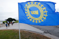 In this Sept. 30, 2019, file photo, a UAW flag flies near strikers outside the General Motors Orion Assembly plant in Orion Township, Mich.