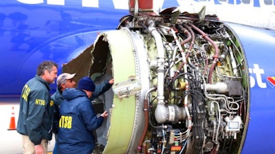 National Transportation Safety Board investigators examine damage to the engine of the Southwest Airlines plane that made an emergency landing at Philadelphia International Airport in Philadelphia on Tuesday, April 17, 2018. The Southwest Airlines jet blew the engine at 32,000 feet and got hit by shrapnel that smashed a window, setting off a desperate scramble by passengers to save a woman from getting sucked out. She later died, and seven others were injured.