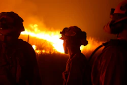 In this Sept. 12, 2015 file photo, California Department of Corrections and Rehabilitation inmates stand guard as flames from the Butte Fire approach a containment line near San Andreas, Calif. California Gov. Gavin Newsom is stepping up pressure on Pacific Gas and Electric to fork over billions more in cash to pay thousands of people whose homes burned in wildfires that drove the utility into bankruptcy. The rising tensions were expected to surface at a hearing Wednesday, Nov. 13, 2019, that has been abruptly postponed by a week.