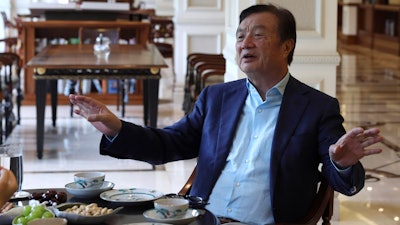 In this Aug. 20, 2019, photo, Huawei's founder Ren Zhengfei gestures as he chats with Huawei executives at the company campus in Shenzhen in Southern China's Guangdong province. Ren says its troubles with President Donald Trump are hardly the biggest crisis he has faced while working his way from rural poverty to the helm of China’s first global tech brand.