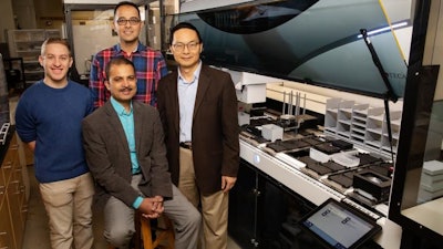 Scott Weisberg, left, professor Saurabh Sinha, seated, Mohammad (Sam) Hamedi Rad and professor Huimin Zhao have combined a fully automated robotic platform with artificial intelligence to develop a new way to manufacture chemicals.