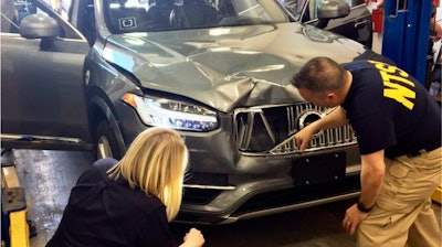 In this March 20, 2018, file photo provided by the National Transportation Safety Board, investigators examine a driverless Uber SUV that fatally struck a woman in Tempe, Ariz.
