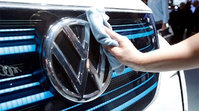 A worker shines the grill of a new Volkswagen electric car during a press conference at the Paris Motor Show, Sept. 29, 2016.