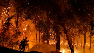 In this Oct. 31, 2019, file photo, a firefighter battles a wildfire in Somis, Calif.