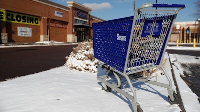 In this Jan. 1, 2019, file photo, an empty shopping cart sits outside a Sears store in the Streets of Southglenn mall in Littleton, Colo.
