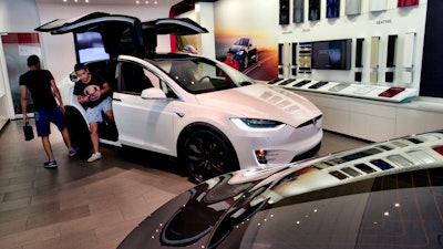 In this Aug. 8, 2018, file photo, customers check out the Tesla X at the Tesla showroom in Santa Monica, Calif.