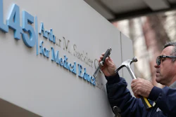 Worker Gabe Ryan removes a sign that includes the name Arthur M. Sackler at an entrance to Tufts School of Medicine, Dec. 5, 2019, in Boston.