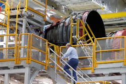 An employee walks up to two of the four rocket engines of NASA's Space Launch System as the Artemis 1 rocket core stage is assembled at the NASA Michoud Assembly Center in New Orleans, Dec. 9, 2019.