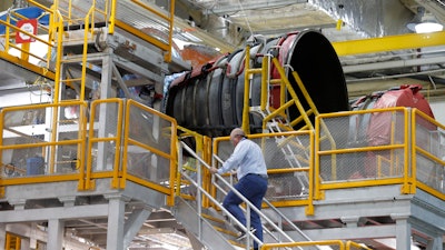 An employee walks up to two of the four rocket engines of NASA's Space Launch System as the Artemis 1 rocket core stage is assembled at the NASA Michoud Assembly Center in New Orleans, Dec. 9, 2019.