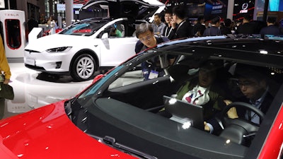 In this April 17, 2019, photo, attendees take a look at electric cars from Tesla at the Auto Shanghai 2019 show.