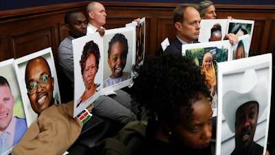Family members of people who died in crashes of the Boeing 737 Max hold photographs of their lost loved ones as FAA Administrator Stephen Dickson testifies during a House Transportation Committee hearing, Dec. 11, 2019, on Capitol Hill.
