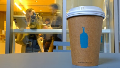 In this Dec. 12, 2019 photo, a Blue Bottle Coffee paper to-go cup rests on a table outside one of their cafes in San Francisco.