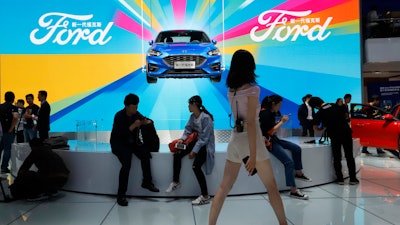 In this April 25, 2018, file photo, attendees visit the Ford booth during Auto China 2018 in Beijing.
