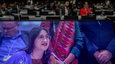 A member of IFAD farmer is seen on the screen during a closing speed at the COP25 closing plenary in Madrid, Dec. 15, 2019.