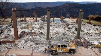 In this Dec. 3, 2018, file photo, a vehicle rests in front of a home leveled by the Camp Fire in Paradise, Calif.