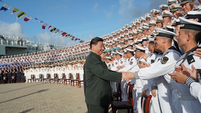 In this photo provided by China's Xinhua News Agency, Chinese President Xi Jinping meets with representatives of the aircraft carrier unit and the manufacturer at a naval port in Sanya, Dec. 17, 2019.