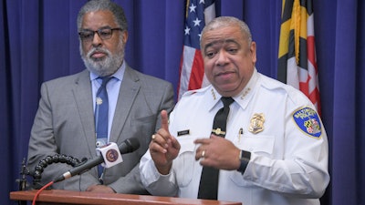 City solicitor Andre Davis, left, listens as Baltimore Police Commissioner Michael Harrison, right, announces support for a pilot program that uses surveillance planes over the city to combat crime, Dec. 20, 2019, in Baltimore.