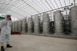 In this Nov. 12, 2014, file photo, a Tokyo Electric Power Co. official wearing a radioactive protective gear stands in front of Advanced Liquid Processing Systems during a press tour at the Fukushima Dai-ichi nuclear power plant in Okuma