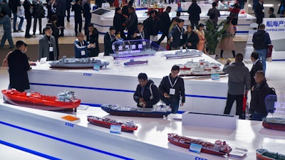 In this Dec. 3, 2019, photo, visitors look at the ship models exhibited by the China State Shipbuilding Corporation during the Marintec China exhibition in Shanghai.