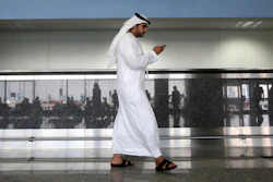 In this Oct. 27, 2013, file photo, a worker looks at his mobile phone at the newly opened Al Maktoum International Airport in Dubai.