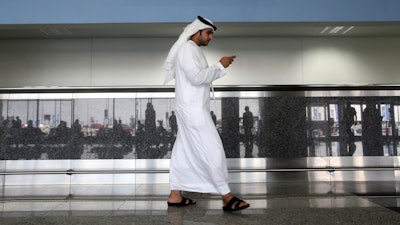 In this Oct. 27, 2013, file photo, a worker looks at his mobile phone at the newly opened Al Maktoum International Airport in Dubai.