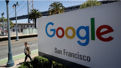 In this May 1, 2019, file photo, a man walks past a Google sign in San Francisco.