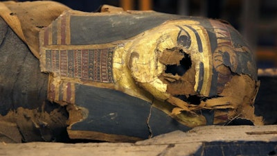 In this Dec. 5, 2014, photo, the mummified body of Minirdis, a 14-year-old Egyptian boy, and his burial mask in an opened coffin at the Field Museum in Chicago.