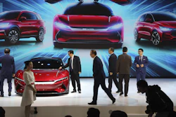 In this April 16, 2019, photo, attendees look at cars from BYD at Auto Shanghai.