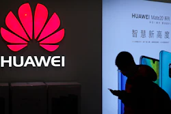 In this Dec. 11, 2018, photo, a man browses his smartphone outside a Huawei store at a shopping mall in Beijing.