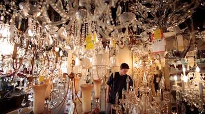 In this Jan. 21, 2011, file photo, Jack George, an employee at Royal Lighting, looks at chandeliers using incandescent light bulbs at the store in Los Angeles.