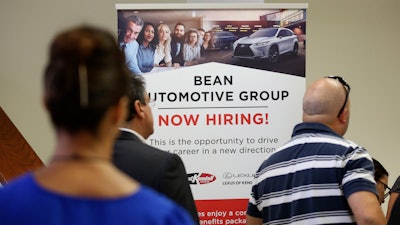In this Sept. 18, 2019, file photo, people stand in line to inquire about jobs available at the Bean Automotive Group during a job fair in Miami.
