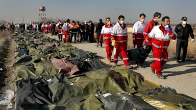 Rescue workers carry the body of a victim of a plane crash in Shahedshahr, Iran, Jan. 8, 2020.