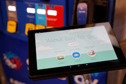 An employee holds a tablet demonstrating the Alexa pay for gas feature in the Amazon booth at the CES tech show, Jan. 8, 2020, in Las Vegas.