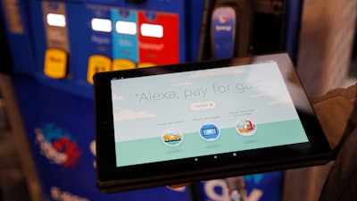 An employee holds a tablet demonstrating the Alexa pay for gas feature in the Amazon booth at the CES tech show, Jan. 8, 2020, in Las Vegas.