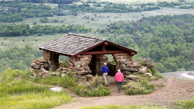 In this June 11, 2014, file photo, visitors hike to a stone lookout over the Little Missouri River inside the Theodore Roosevelt National Park, North Dakota.