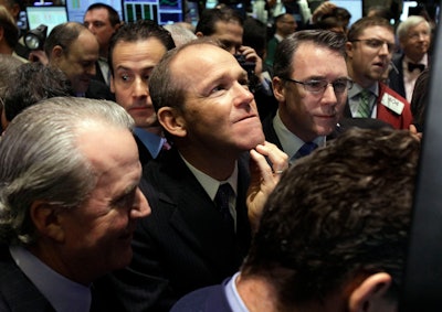 In this Jan. 26, 2011, file photo, Nielsen Company CEO David Calhoun, center, watches progress as he waits for the company's IPO to begin trading on the floor of the New York Stock Exchange.