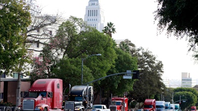 In this Nov. 13, 2009, file photo, a caravan of trucks from the ports of Los Angeles and Long Beach, Calif., drive around Los Angeles City Hall during a protest against container fees on independent truckers.