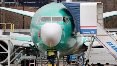 In this Dec. 16, 2019, file photo, a worker looks up underneath a Boeing 737 Max jet, Renton, Wash.