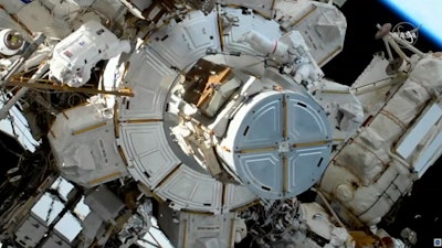 In this image take from NASA video, astronaut Christina Koch, left, moves away as Jessica Meir, right, exits a hatch as they prepare to install batteries for the International Space Station's solar power grid, Jan. 20, 2020.