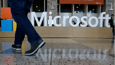 In this April 28, 2015, file photo, a man walks past a Microsoft sign at Moscone Center in San Francisco.