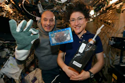 In this photo made available by U.S. astronaut Christina Koch via Twitter on Dec. 26, 2019, she and Italian astronaut Luca Parmitano pose for a photo with a cookie baked on the International Space Station.